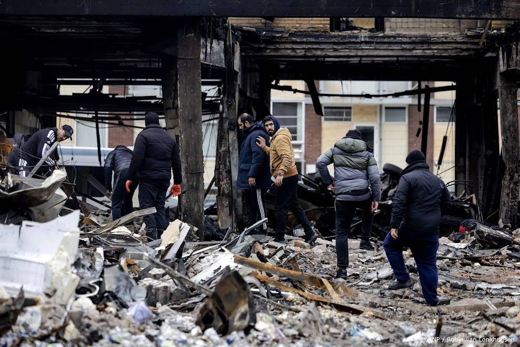 Mannen klimmen over omheining op plaats explosie Rotterdam
