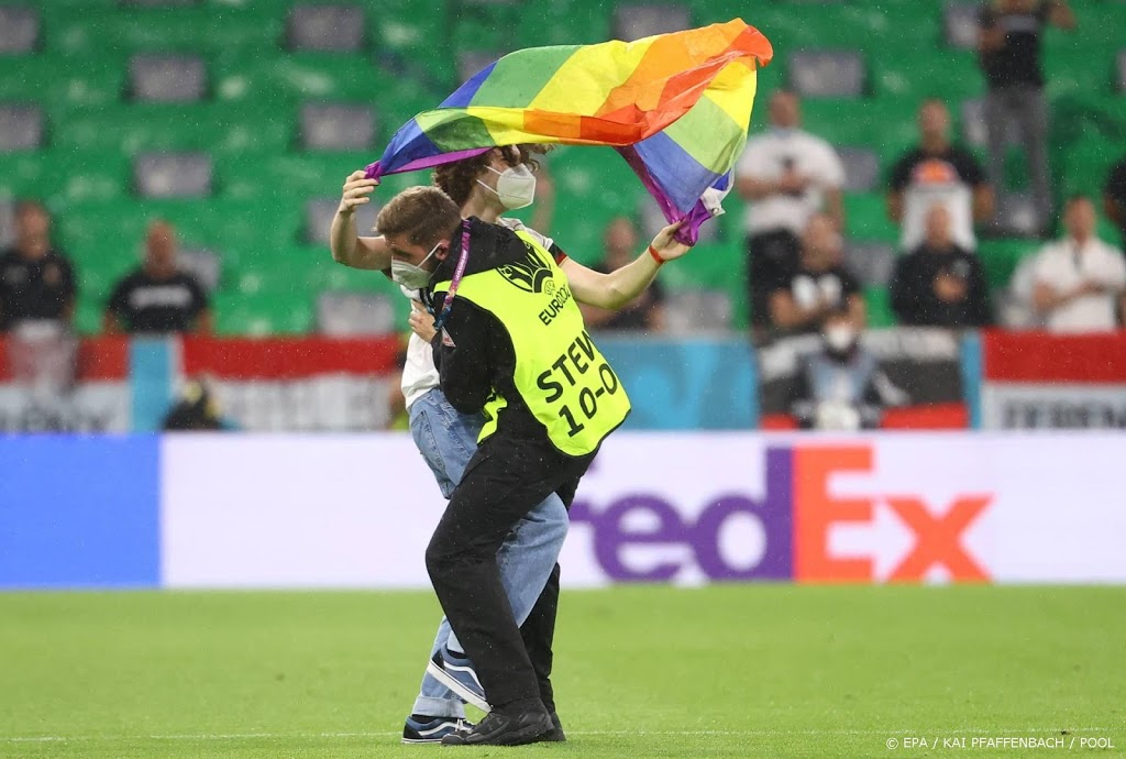 Demonstrant met regenboogvlag op het veld bij Hongaars volkslied