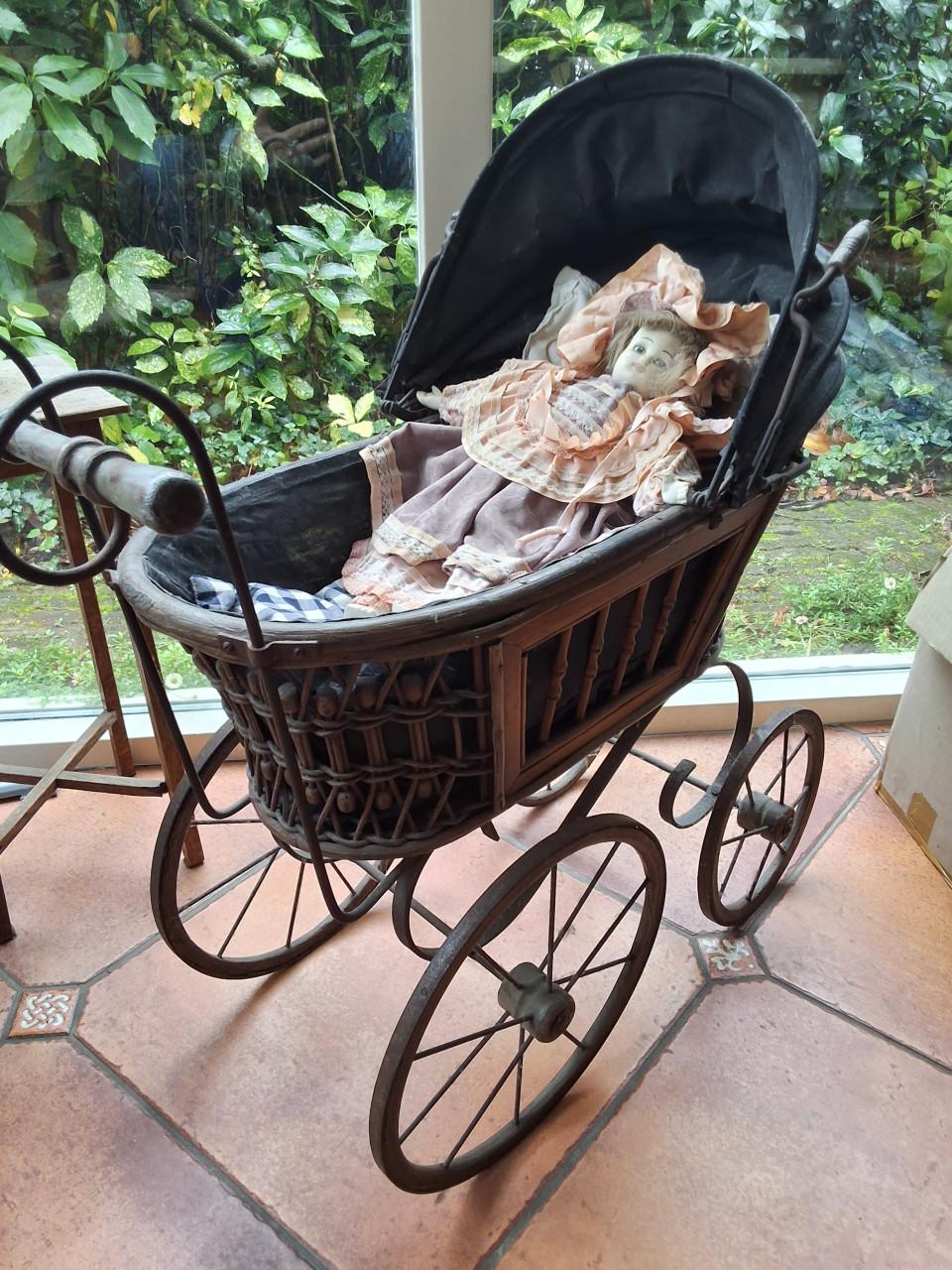 Antieke poppenwagen met porseleinen pop