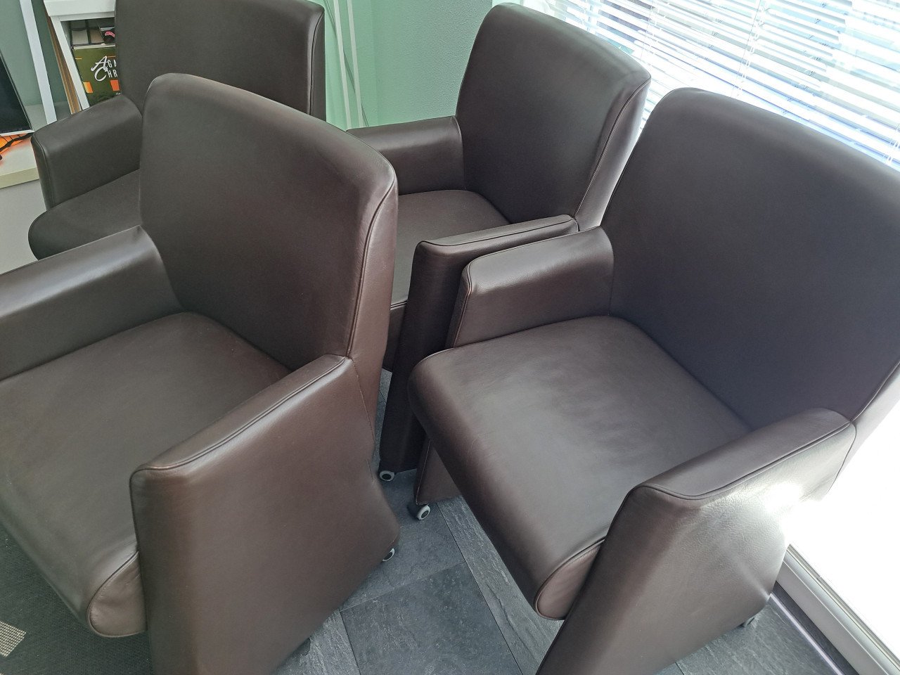 4 bruine kunstlederen stoelen op wieltjes