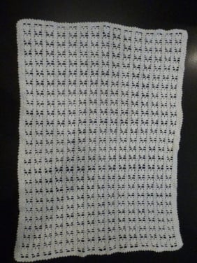 Wit gehaakte baby omslagdoek met hartjes.