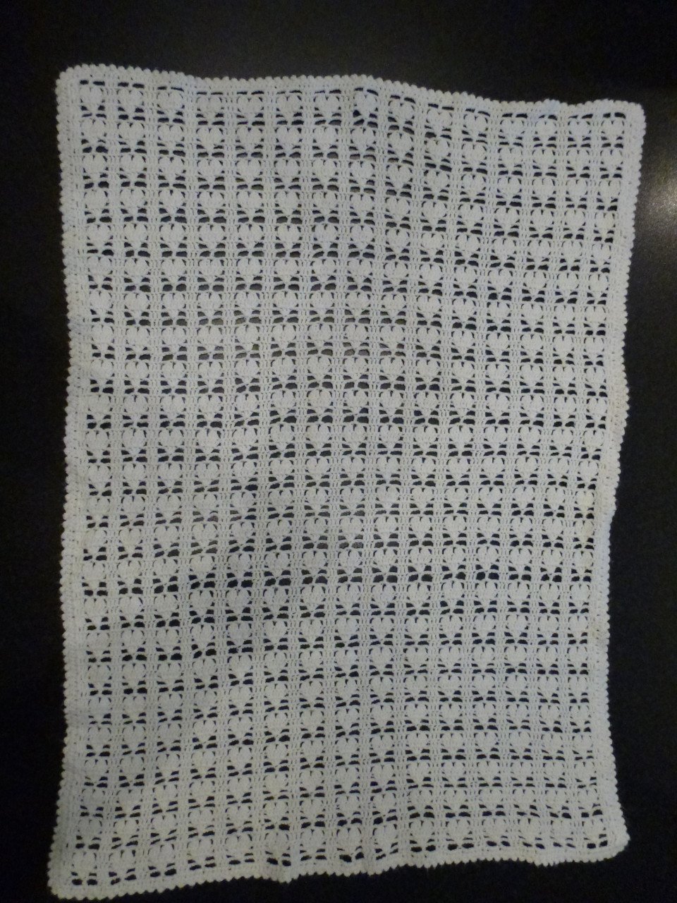 Wit gehaakte baby omslagdoek met hartjes.