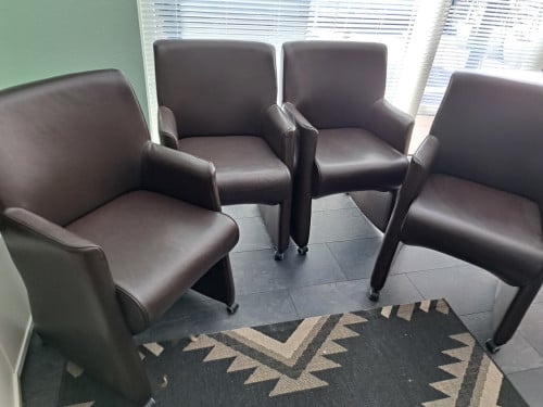 4 bruine kunstlederen stoelen op wieltjes