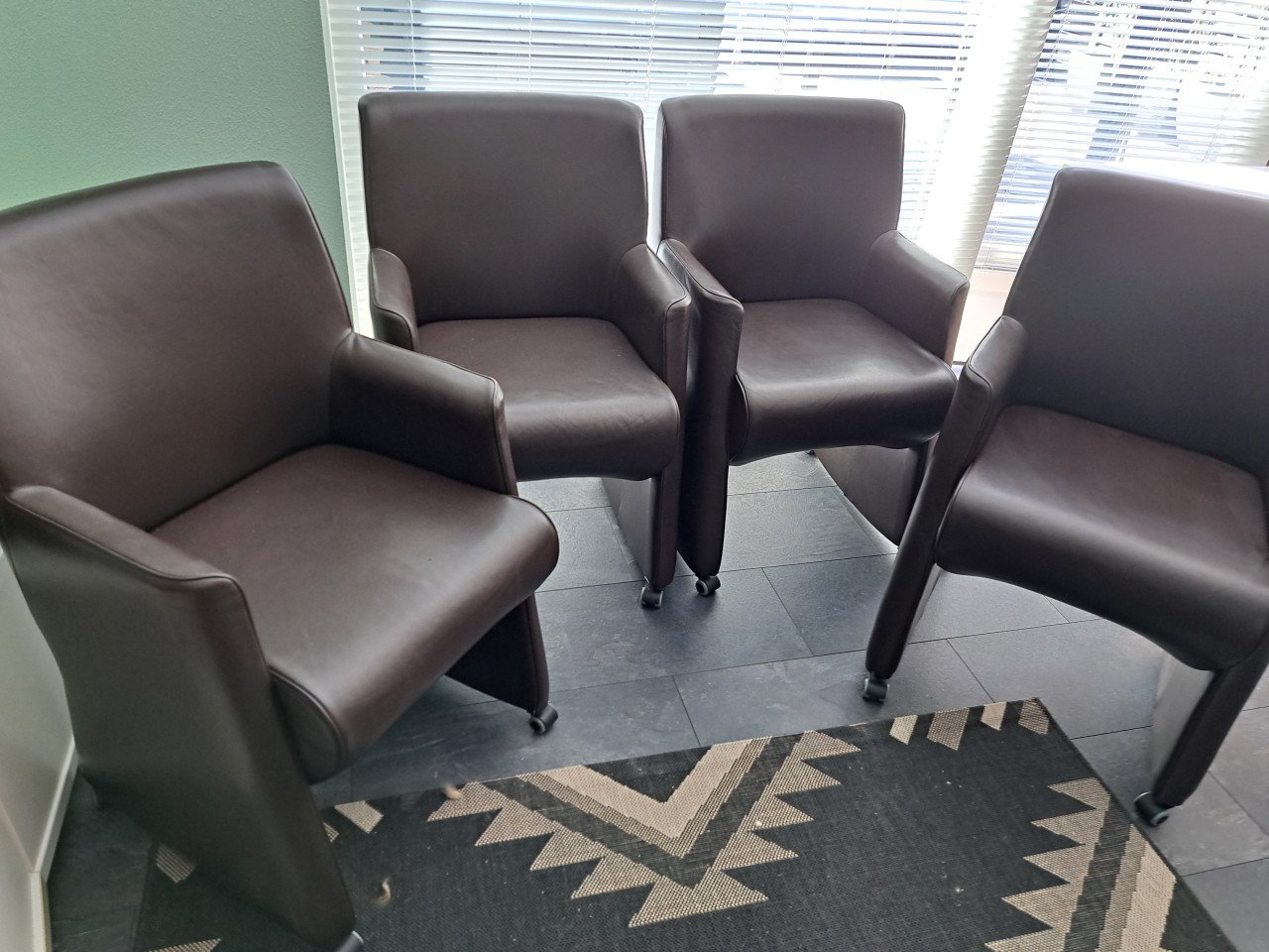 4 bruine kunstlederen stoelen op wieltjes