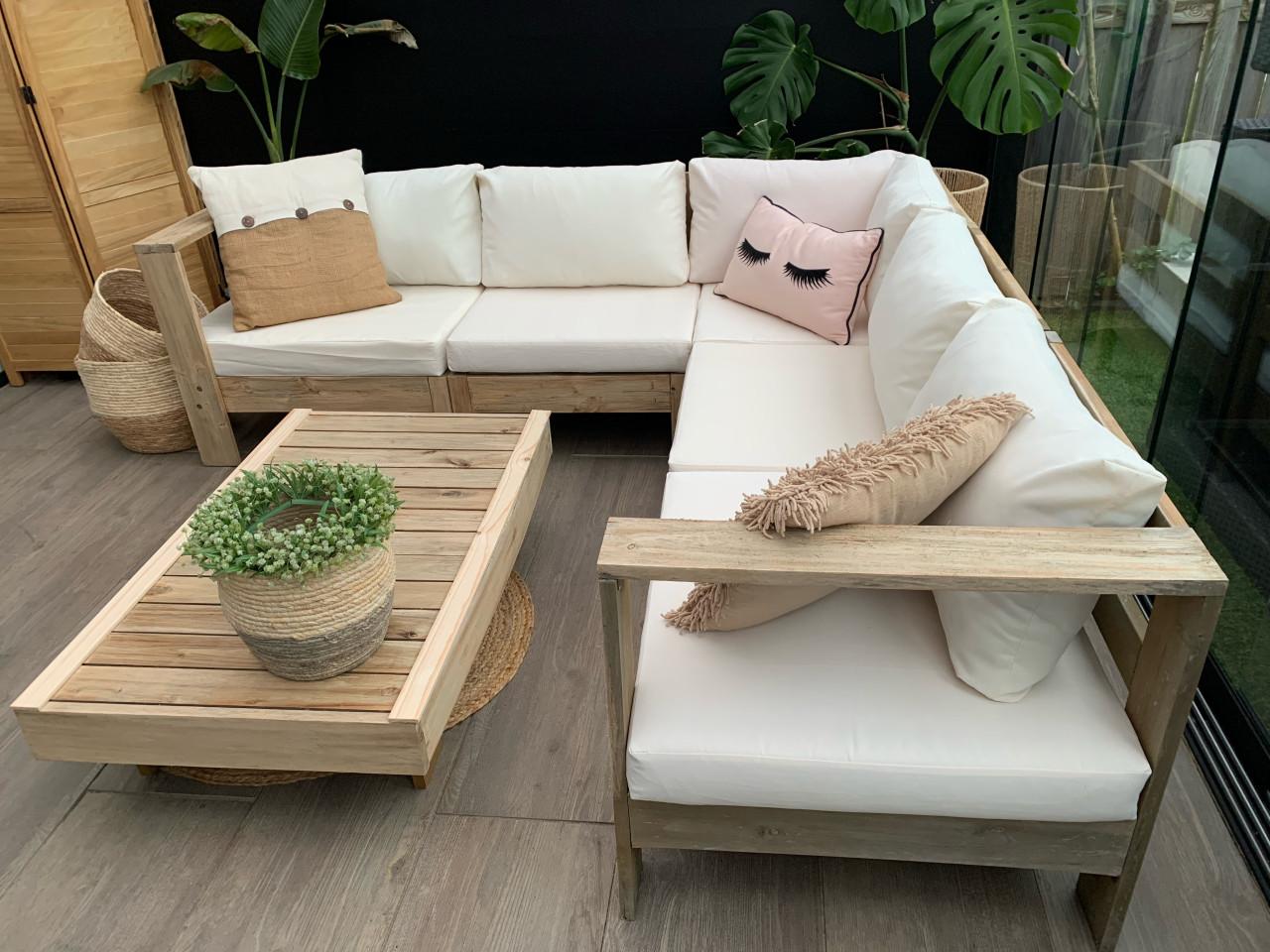 Loungeset van naturel hout met kussens en tafel.