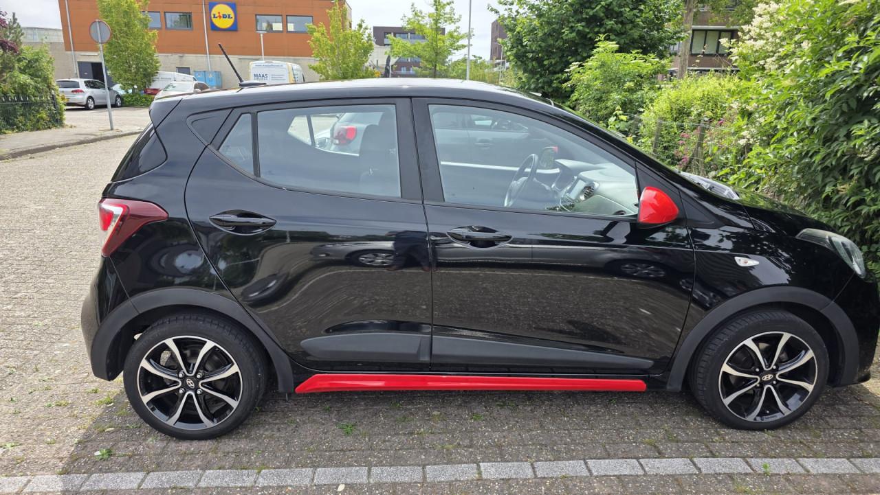 Hyundai I10 2019 met 69300 km Zwart met rode spiegels en sierstrippen.