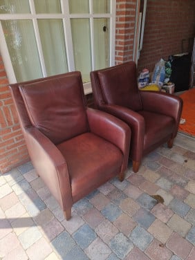 2 roodbruine leren stoelen met houten poten
