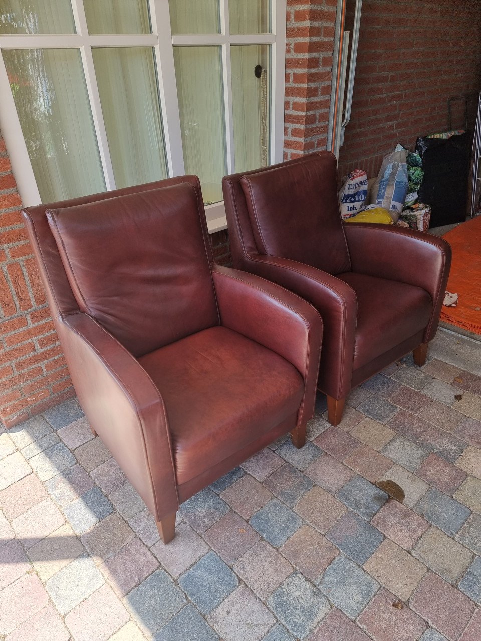 2 roodbruine leren stoelen met houten poten