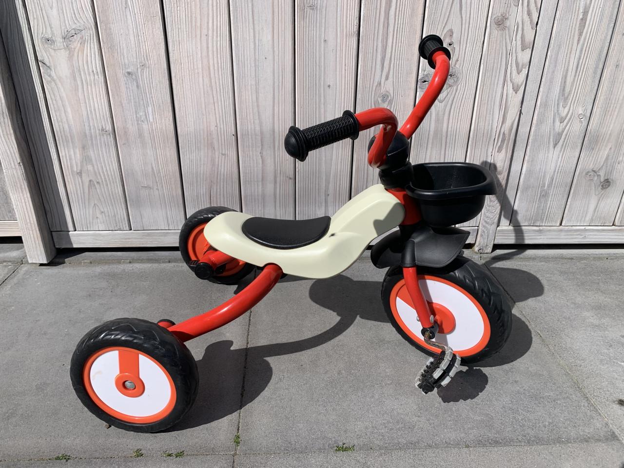 Rode driewieler met een beige zitting en zwarte handvatten