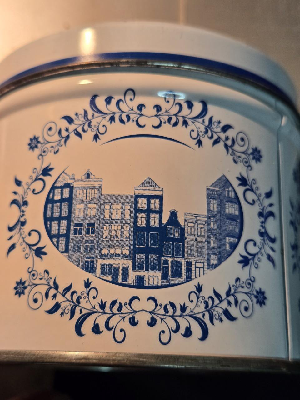 Delfts blauw stroopwafelblik met Amsterdamse grachtenpandjes.