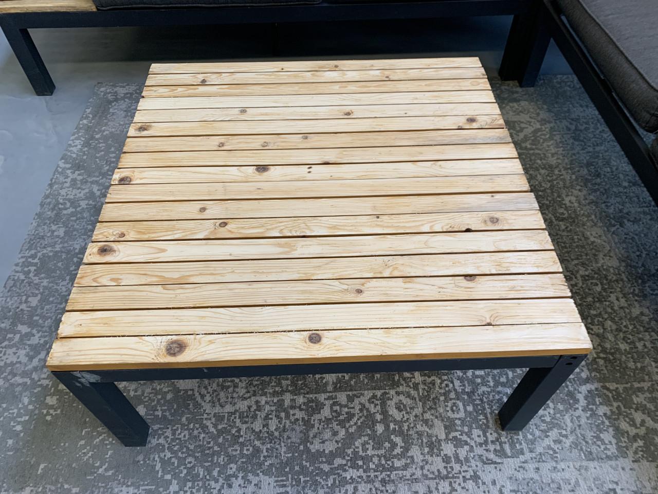 Zwart aluminium loungeset met houten plateaus, en tafel en kussens.