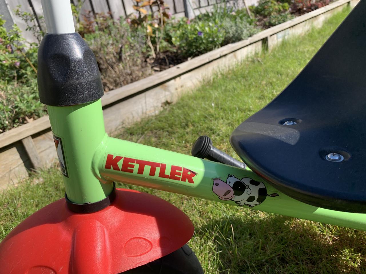 Een groene Kettler driewieler met duwstang