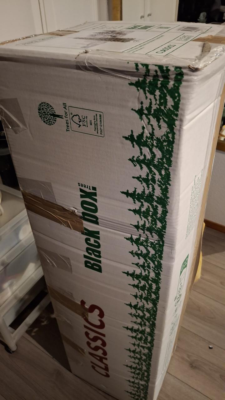 Smalle besneeuwde kerstboom met mand