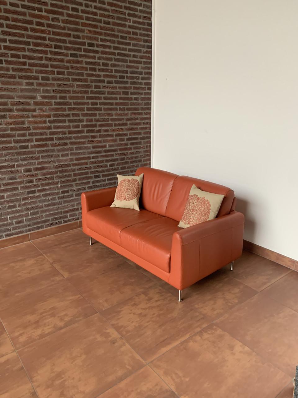 Leuk oranje kleurig bankje met twee kussens