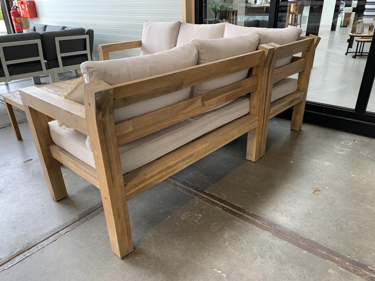 Een houten loungeset met kussens en 2 tafels, en regenhoes