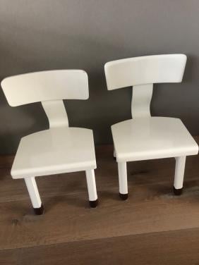 Twee witte houten kleuterstoeltjes.