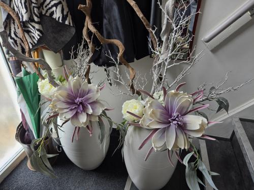2 grote, witte vazen gevuld met decoratieve kunsttakken en kunstbloemen