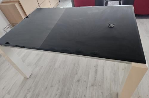 Eettafel van zwart rookglas met witte poten