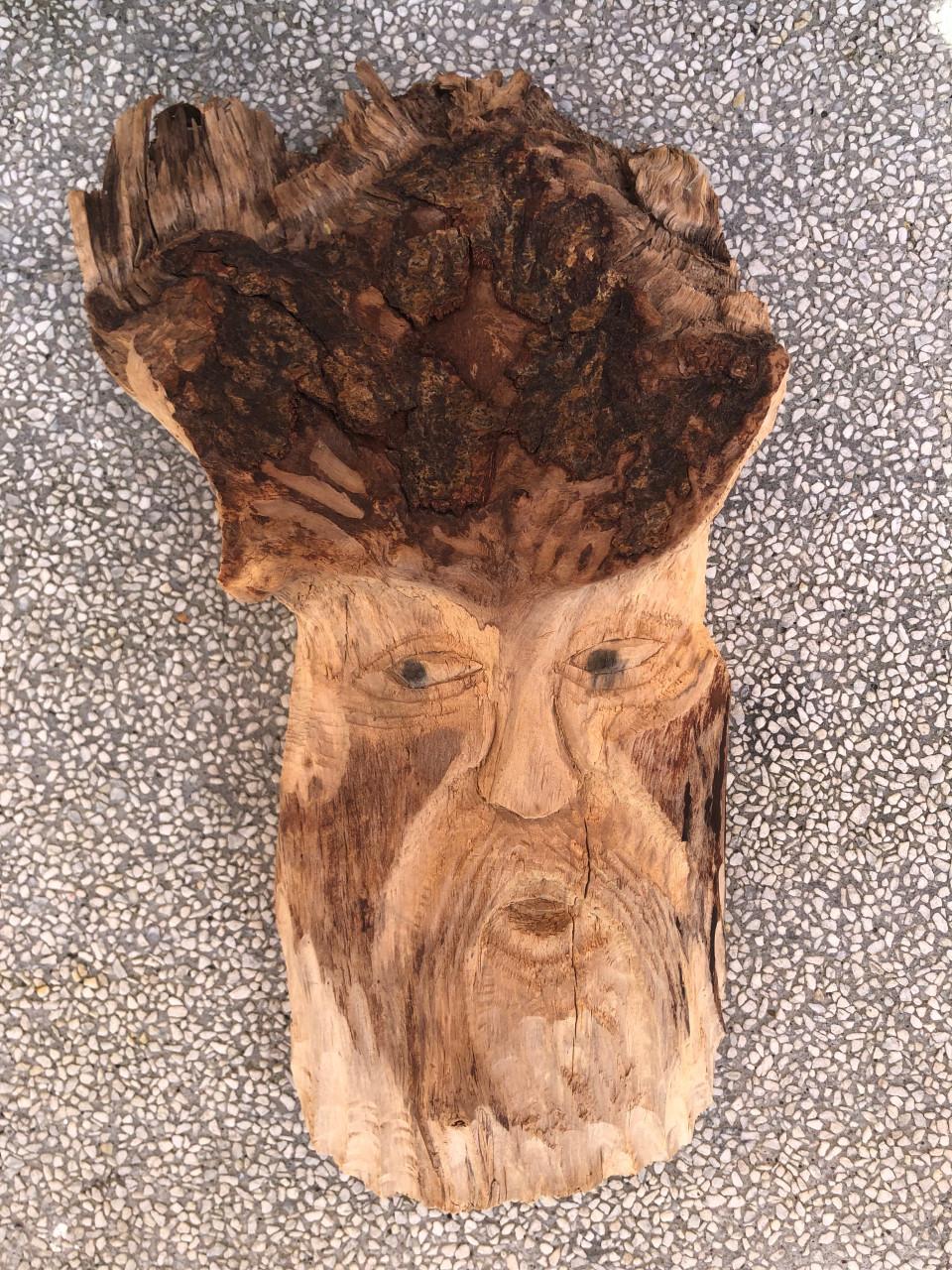 Dit is een houten wanddecoratie in de vorm van een gezicht met baard.