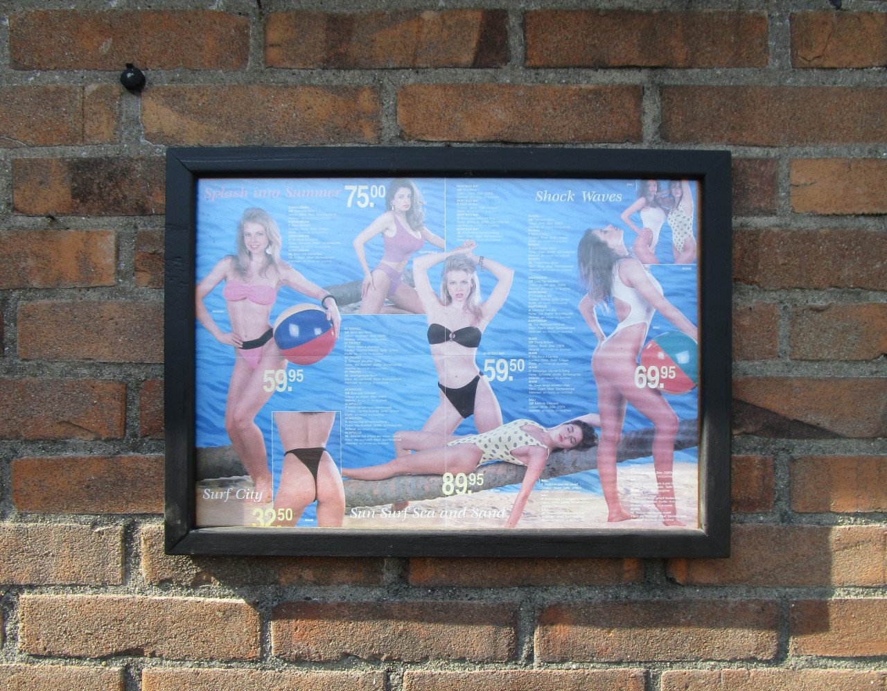 Badkleding in een zwarte lijst achter ontspiegeld glas.