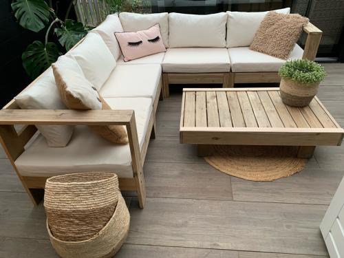 Loungeset van naturel hout met kussens en tafel.