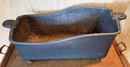 Oude gietijzeren bak voor kolen, houtblokken, kranten en bladen