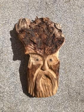 Dit is een houten wanddecoratie in de vorm van een gezicht met baard.