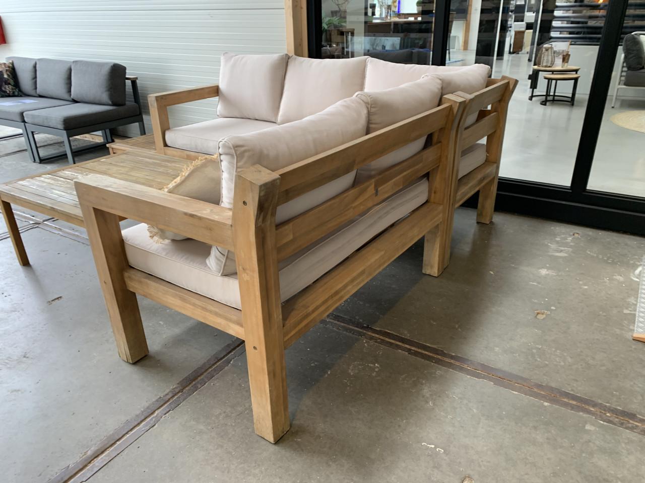 Een houten loungeset met kussens en 2 tafels, en regenhoes