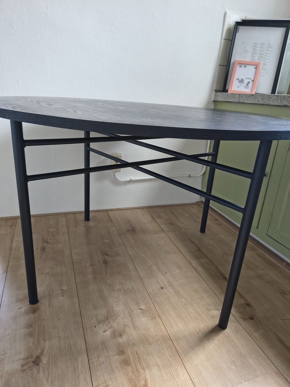 Prachtige ronde houten zwarte eettafel met metalen poten.