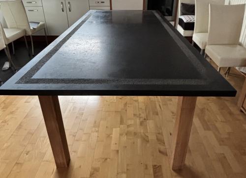 Eettafel met zwart hardstenen blad en poten van teakhout.