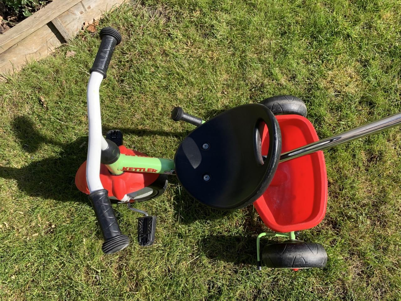 Een groene Kettler driewieler met duwstang