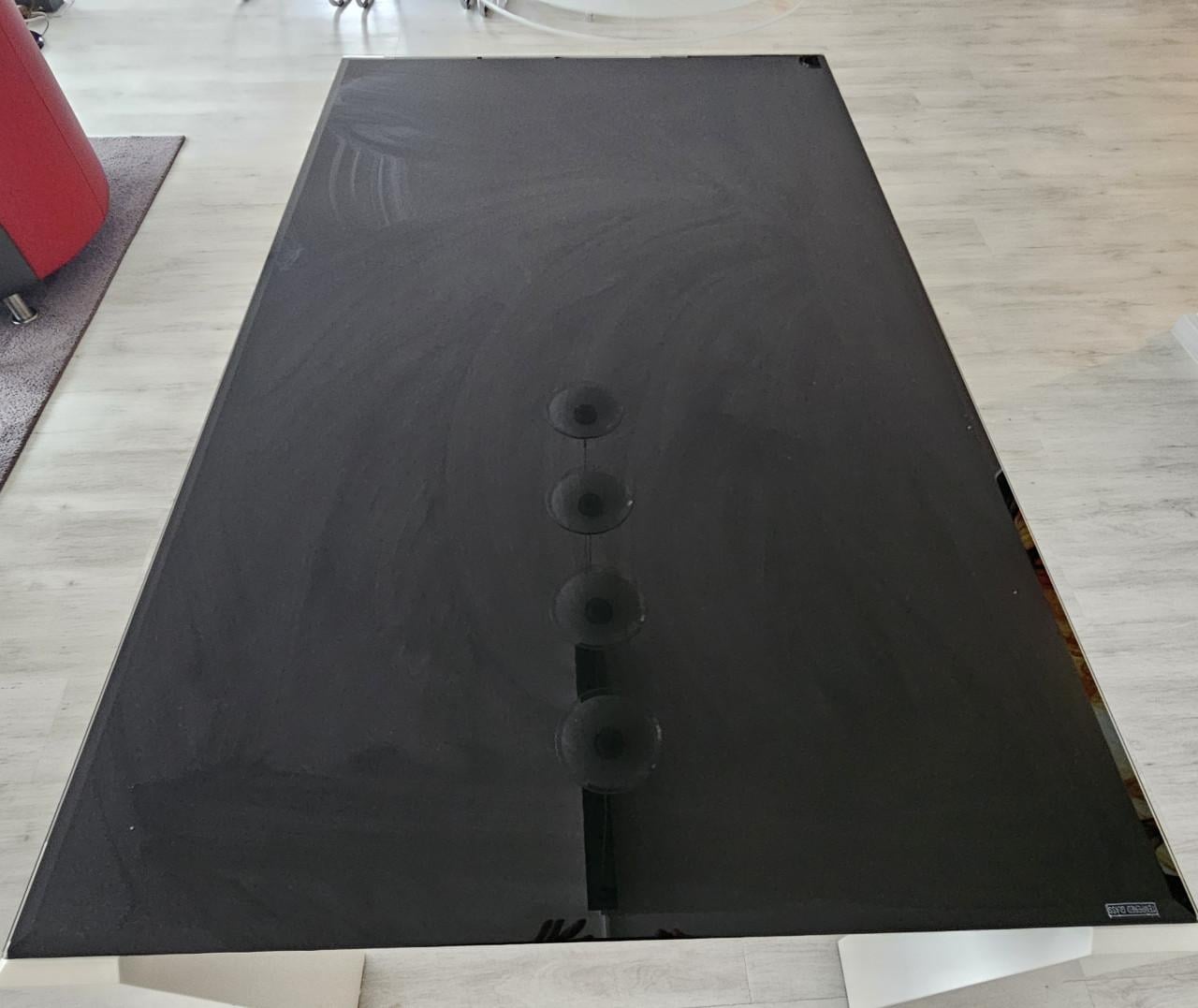 Eettafel van zwart rookglas met witte poten