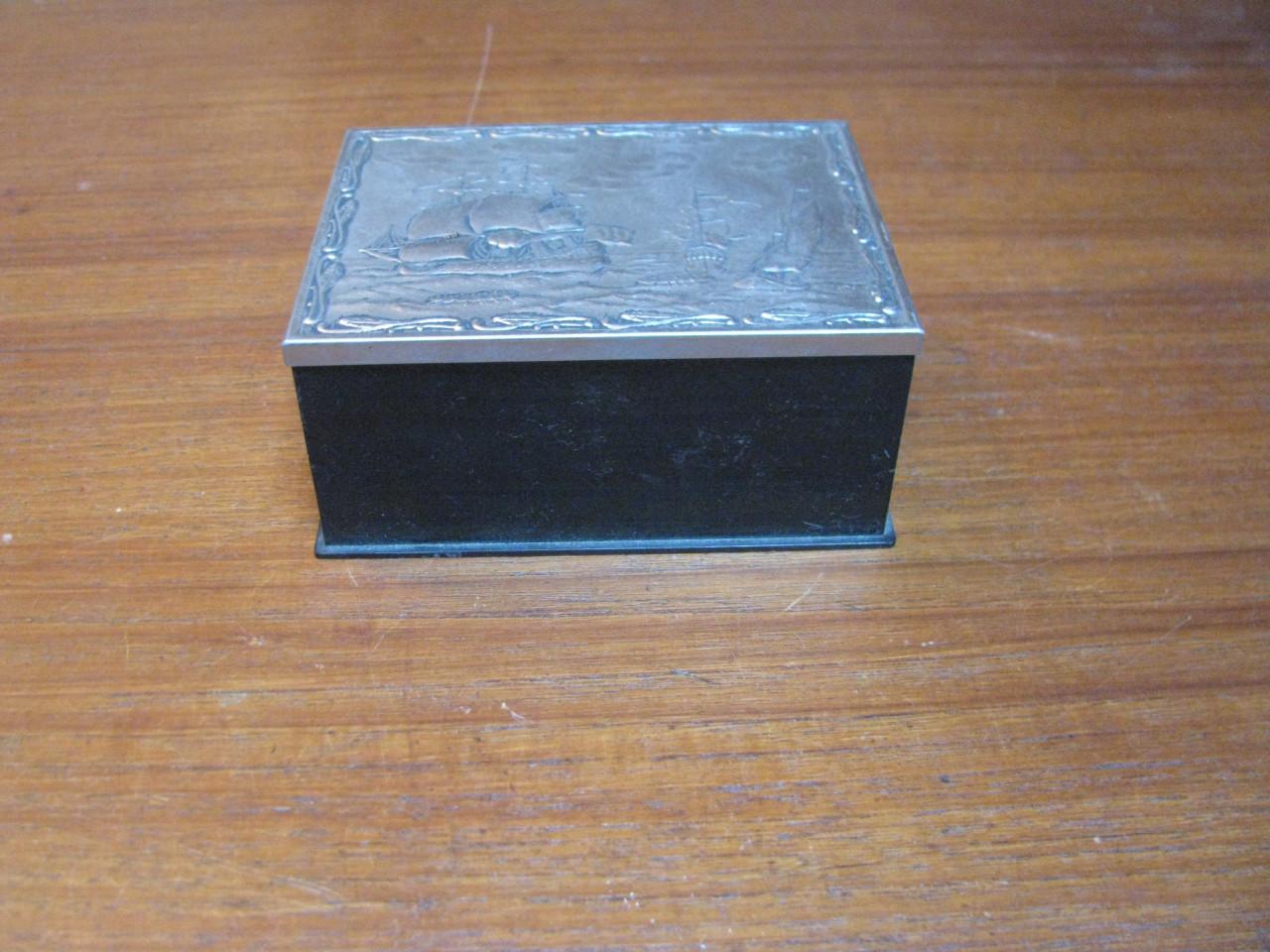 Zwart doosje met zilverkleurig dekseltje.