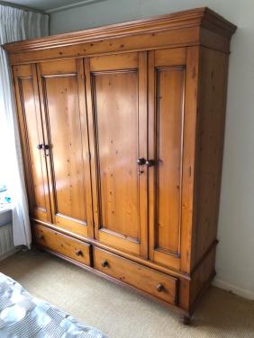 Grote houten kledingkast met deuren en lades.