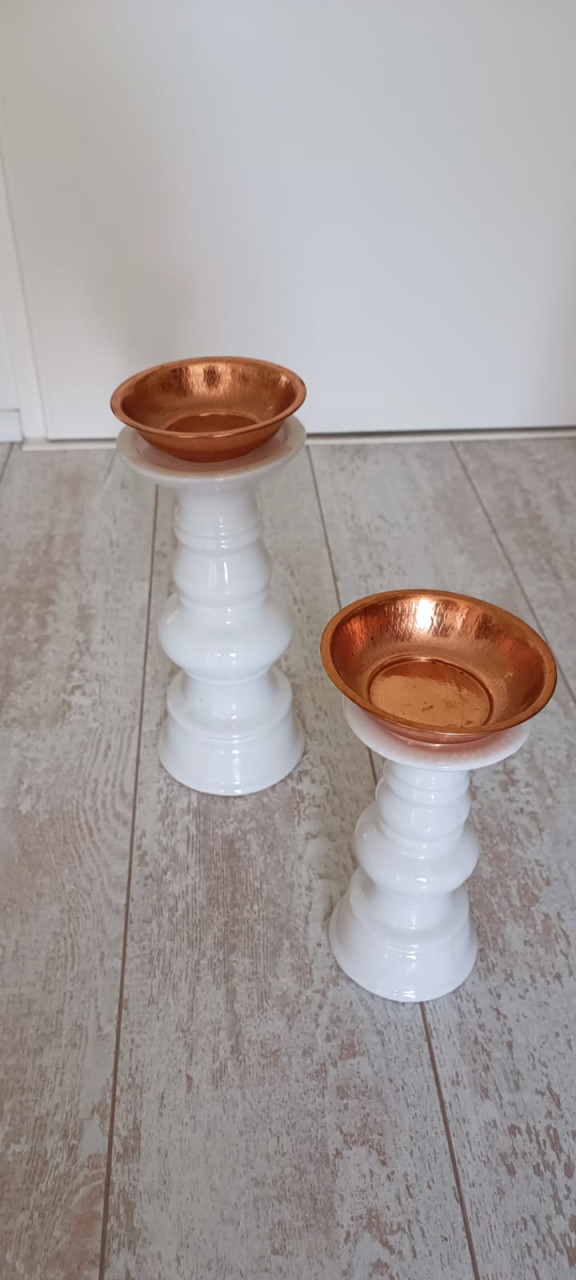 Twee witte kandelaars met koperen bakje