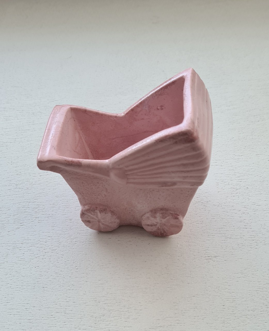 Schattig klein roze bloempotje in de vorm van een kinderwagen