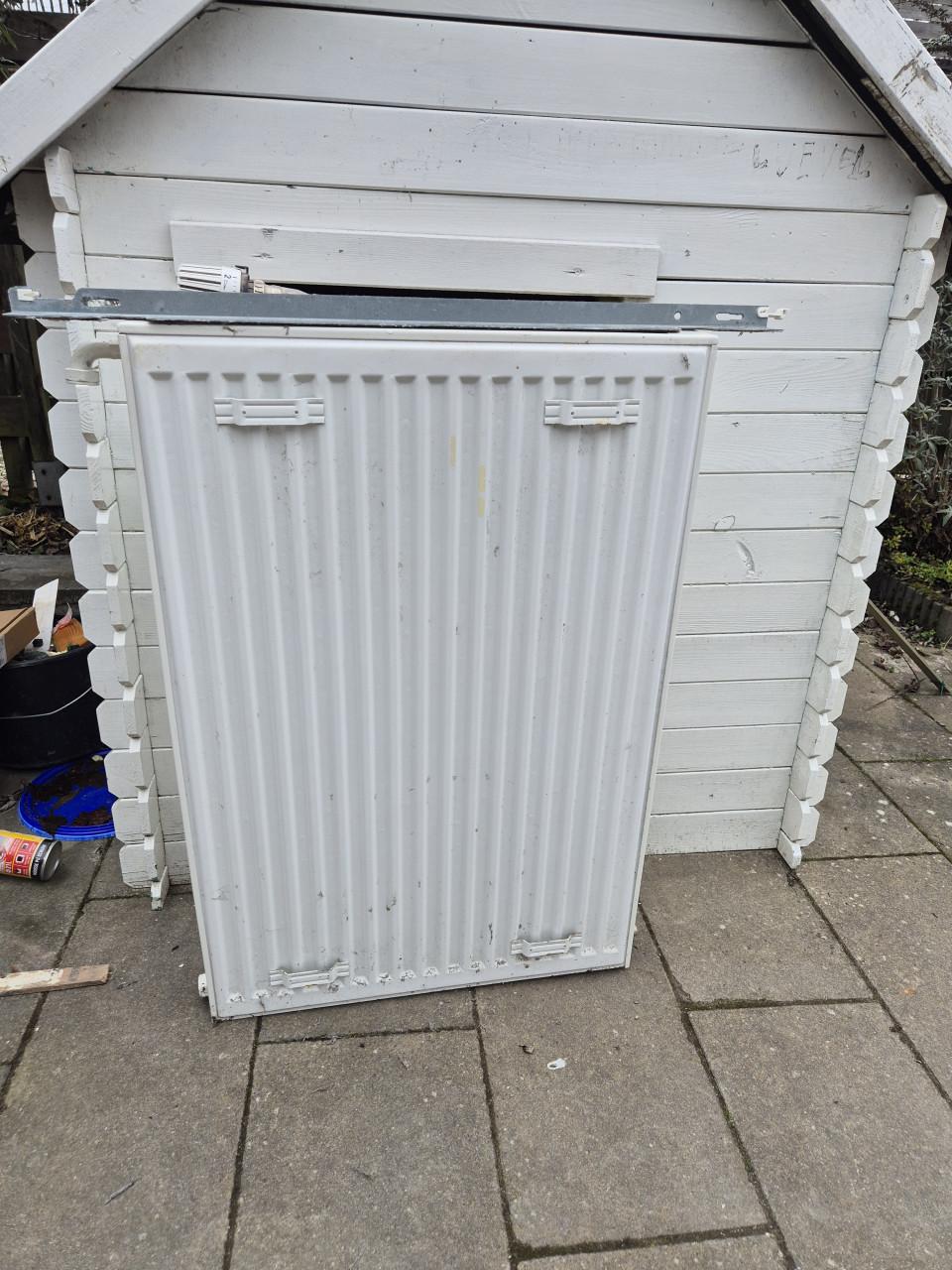 Nette radiator met ophangsysteem en thermostaatknop.