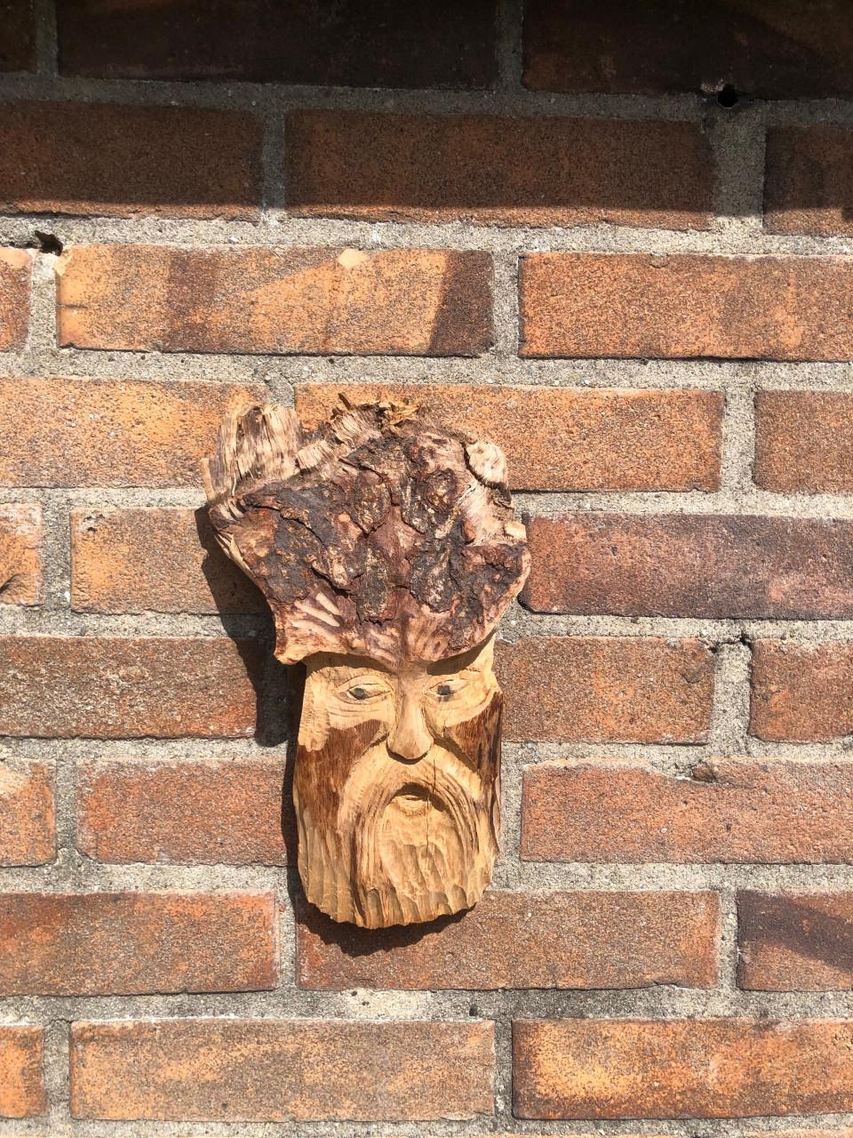 Dit is een houten wanddecoratie in de vorm van een gezicht met baard.