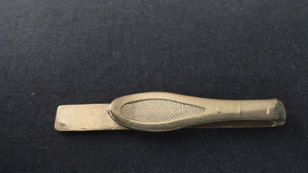 Dasspeld – metaal  Lengte onderkant 5,5 cm. Lengte bovenkant 4 cm.