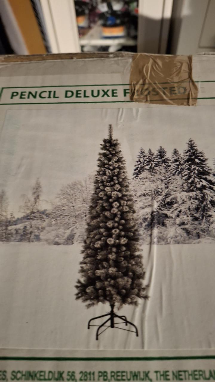 Smalle besneeuwde kerstboom met mand