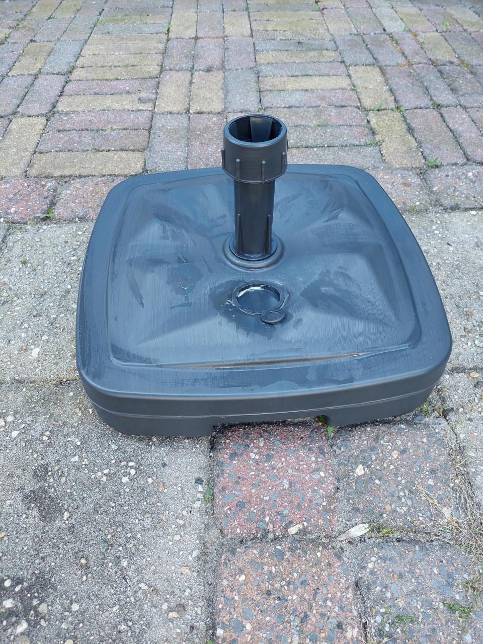 Nieuwe grijze parasolvoet met zand gevuld