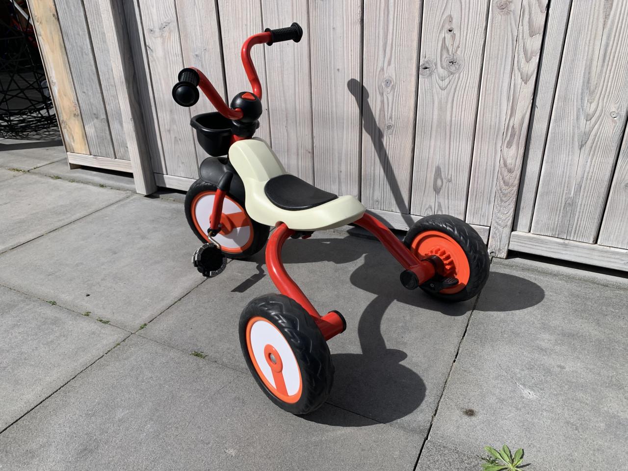 Rode driewieler met een beige zitting en zwarte handvatten