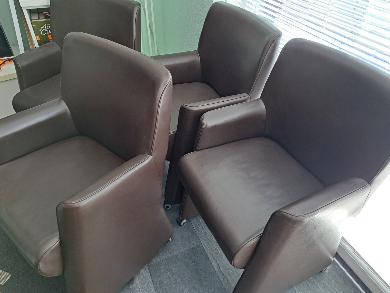 4 bruine kunstlederen stoelen op wieltjes