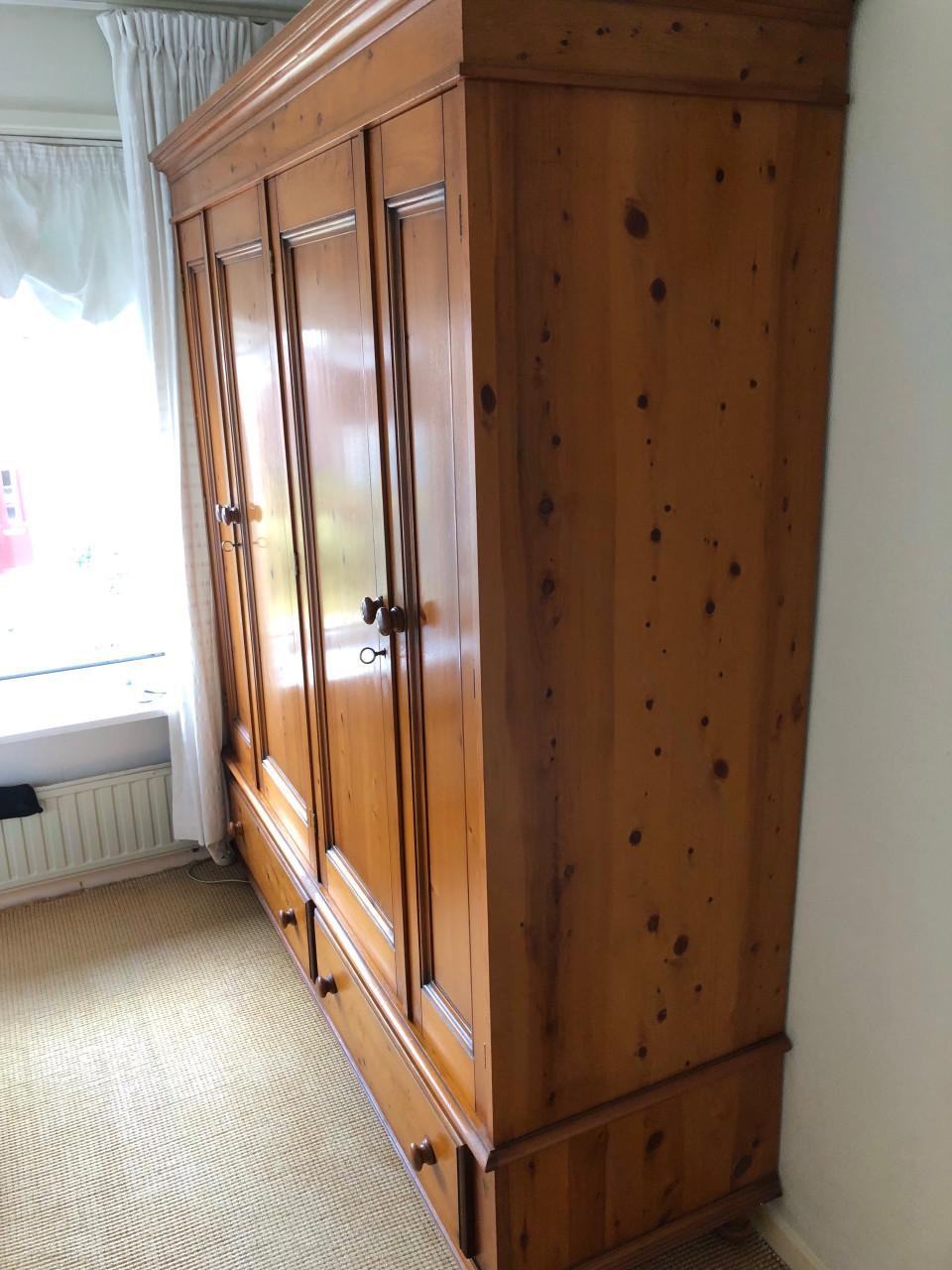 Grote houten kledingkast met deuren en lades.