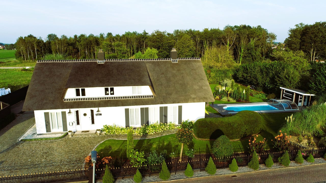 Rietgedekte villa met een overdekt zwembad.