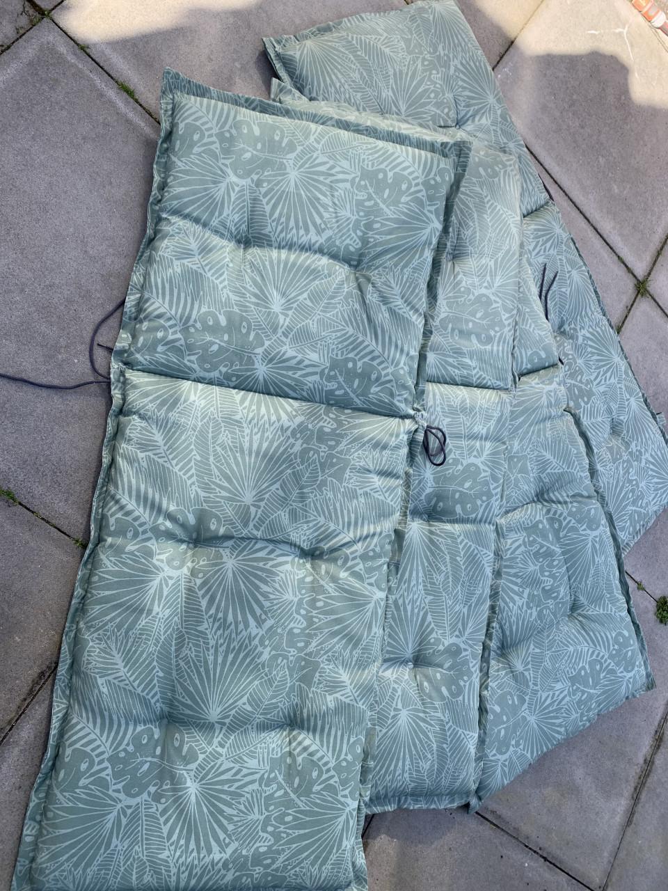 Vier  tuinstoelkussens met een groene bladprint. Met hoes