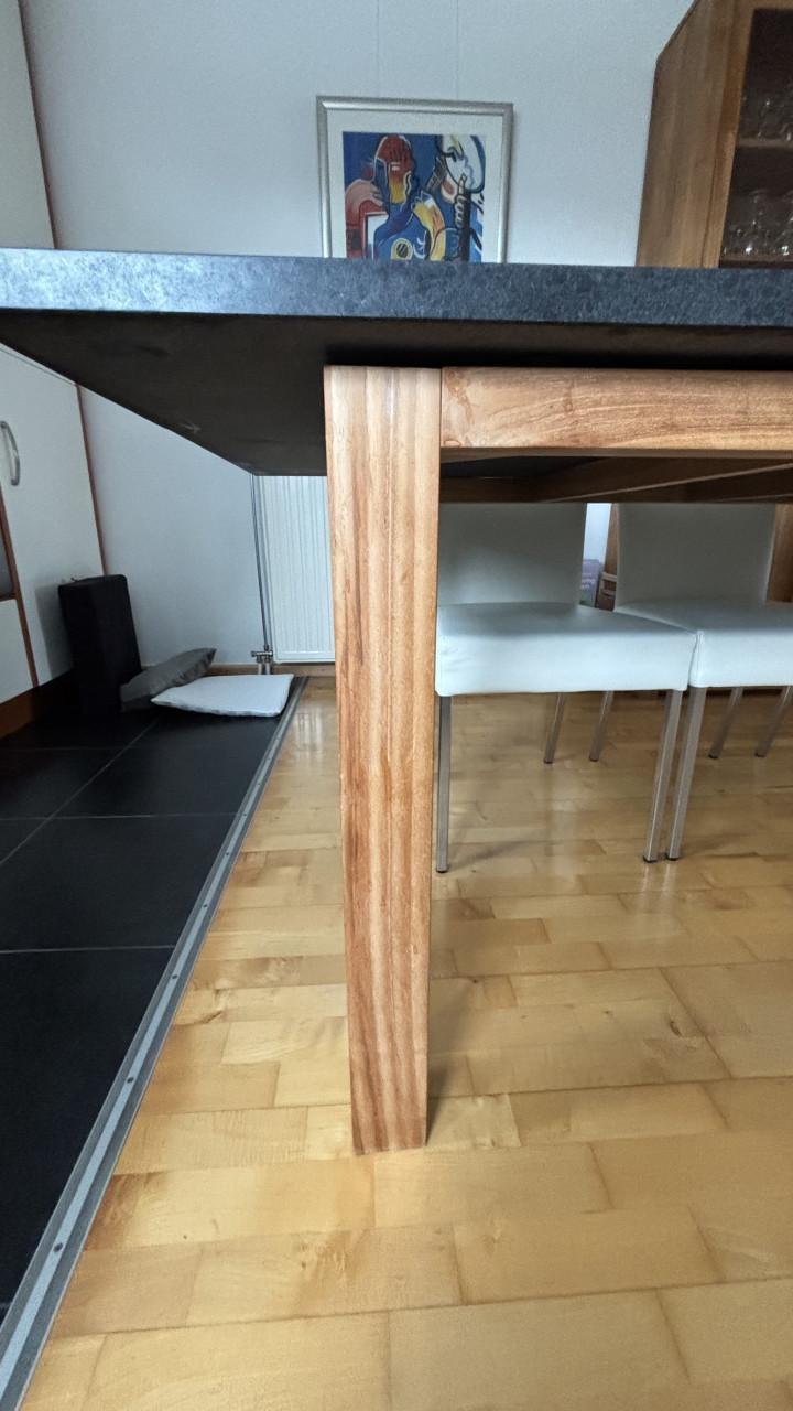 Eettafel met zwart hardstenen blad en poten van teakhout.