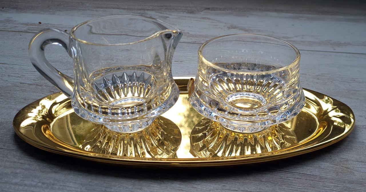 Kristallen melk en suikerset op goudschaal in oogverblindende staat