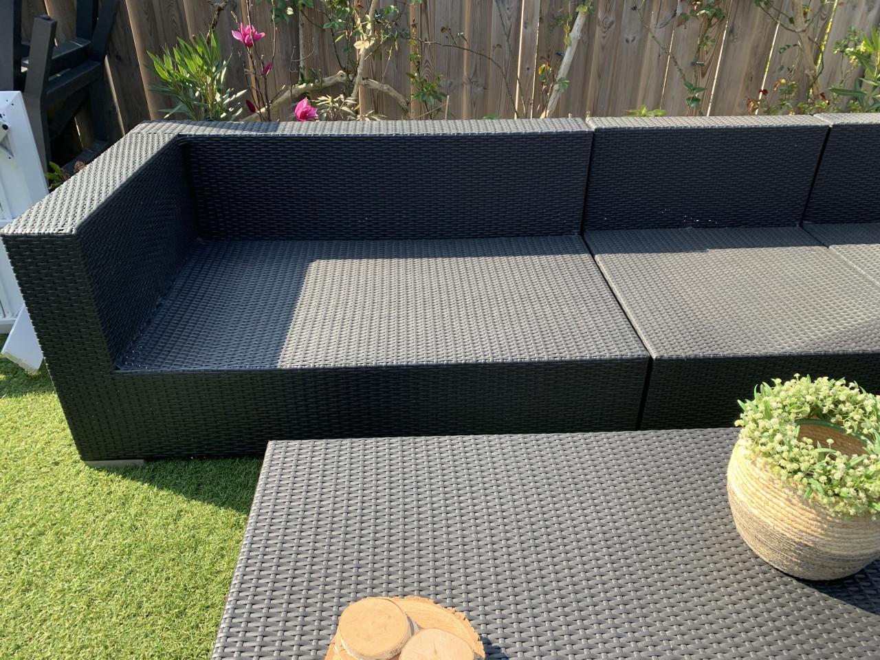 Wicker loungeset zwart met kussens en tafel.