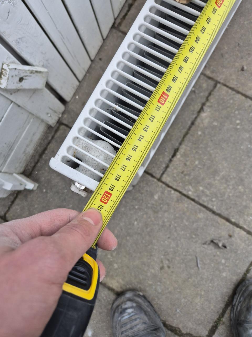 Nette radiator met ophangsysteem en thermostaatknop.